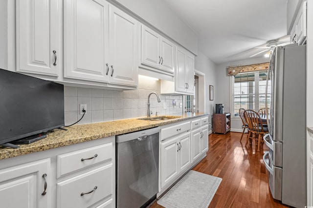 kitchen featuring backsplash, appliances with stainless steel finishes, white cabinets, a ceiling fan, and a sink