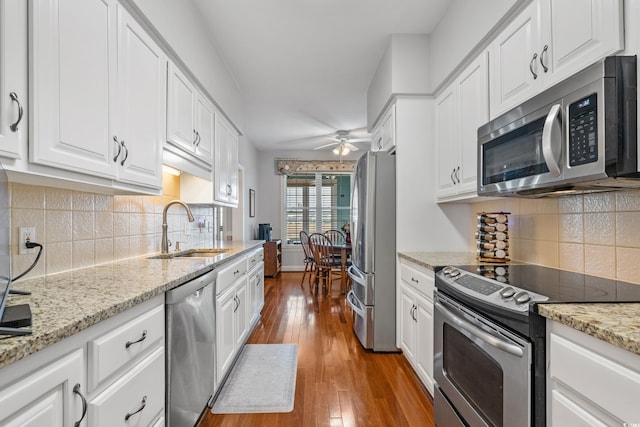 kitchen featuring a ceiling fan, a sink, hardwood / wood-style flooring, appliances with stainless steel finishes, and white cabinetry