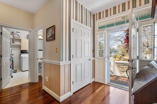 entrance foyer with wainscoting, washer / dryer, wallpapered walls, and dark wood-type flooring