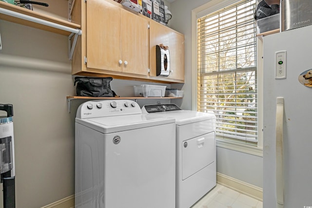 clothes washing area with cabinet space, independent washer and dryer, and baseboards