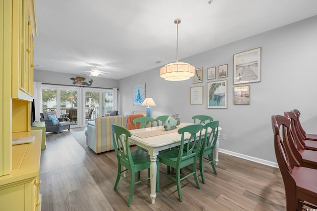 dining area with baseboards, light wood-style floors, and a ceiling fan