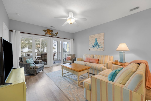 living area featuring a ceiling fan, light wood-style floors, and visible vents