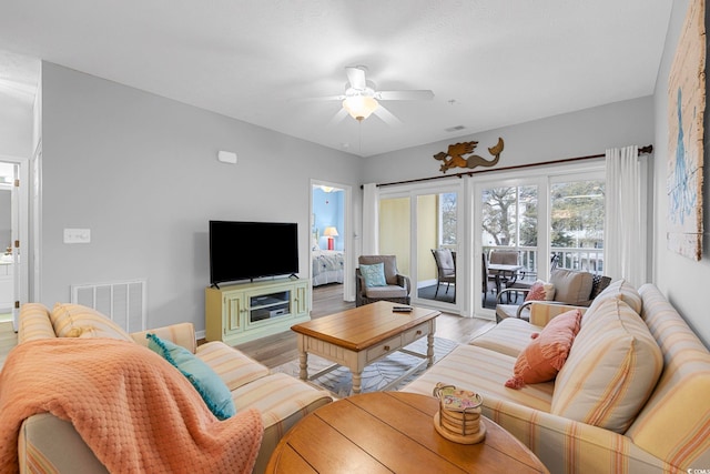 living room with visible vents, baseboards, light wood-type flooring, and a ceiling fan