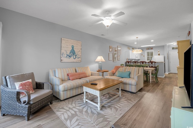 living area with light wood-style flooring and a ceiling fan