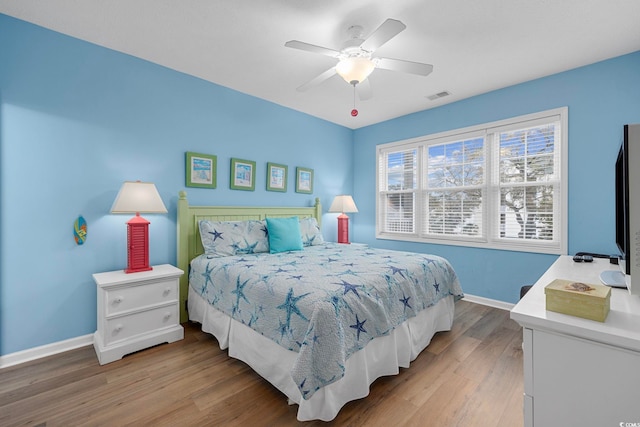 bedroom featuring visible vents, a ceiling fan, baseboards, and wood finished floors