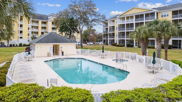 pool featuring a patio, a yard, and fence