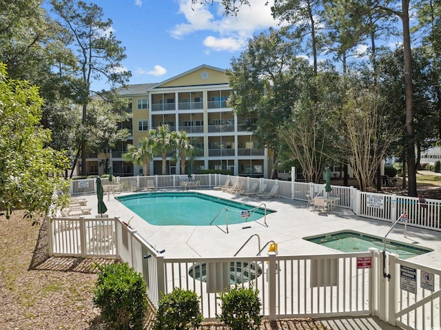 community pool featuring a patio area, a community hot tub, and fence