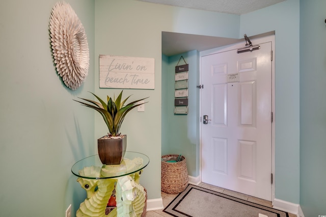 doorway featuring light tile patterned floors and baseboards