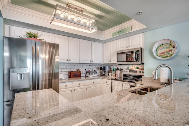 kitchen featuring light stone counters, white cabinetry, stainless steel appliances, and a sink