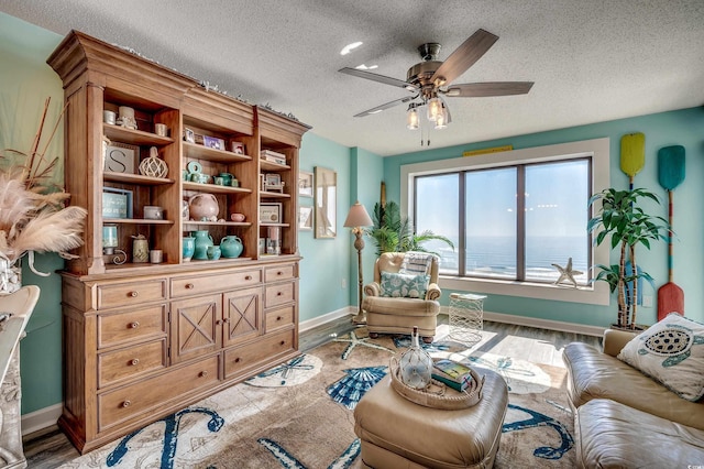 sitting room with a ceiling fan, light wood-type flooring, and a textured ceiling