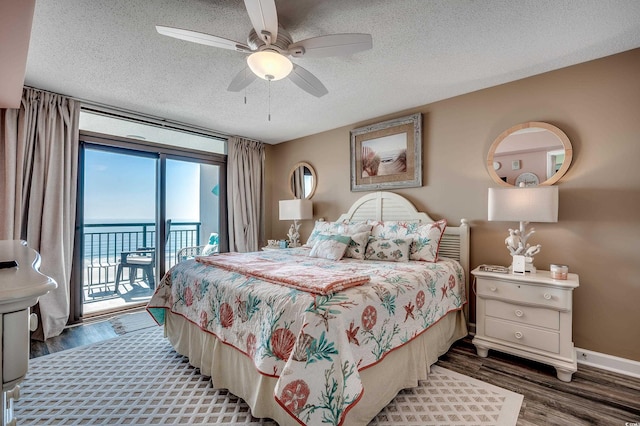 bedroom featuring access to exterior, wood finished floors, baseboards, and a textured ceiling