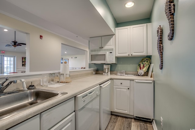 kitchen with a sink, white cabinetry, white appliances, light wood-style floors, and light countertops