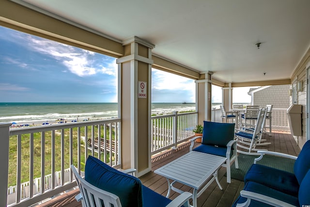 balcony with a water view, a sunroom, and a beach view