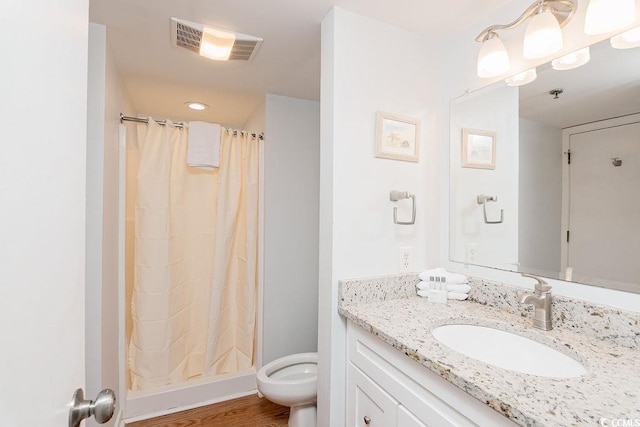 bathroom with vanity, a stall shower, toilet, and wood finished floors