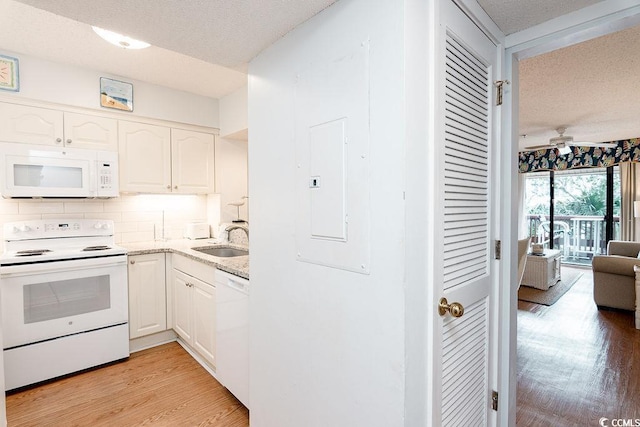 kitchen featuring white appliances, a sink, a textured ceiling, white cabinets, and light wood finished floors