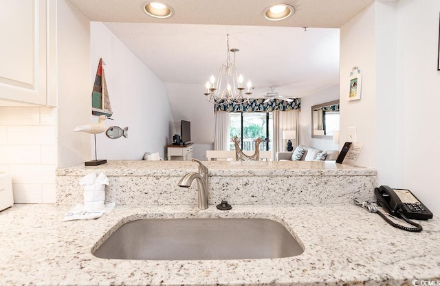 kitchen featuring a sink, light stone counters, a chandelier, tasteful backsplash, and recessed lighting