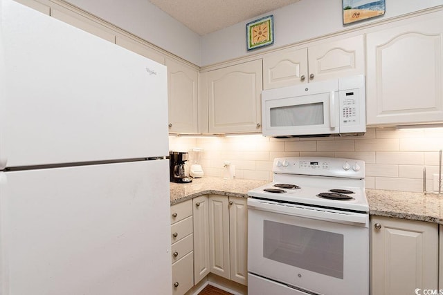 kitchen featuring white appliances, tasteful backsplash, and light stone countertops
