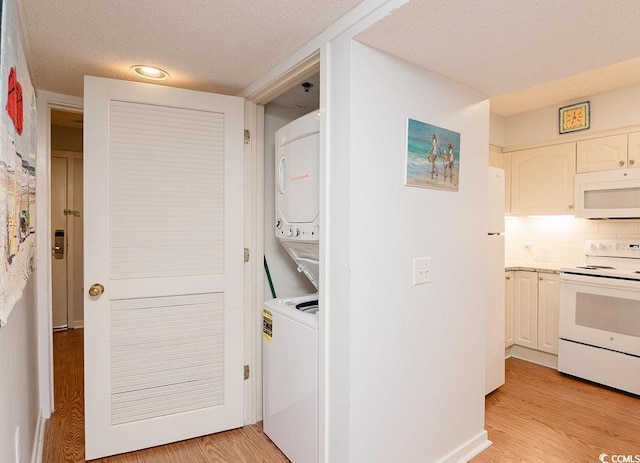 laundry room featuring estacked washer and dryer, light wood finished floors, and a textured ceiling
