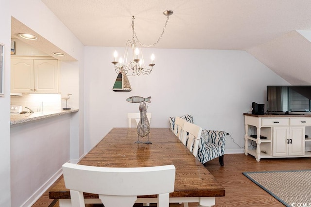 dining space featuring a chandelier, dark wood-type flooring, baseboards, and vaulted ceiling