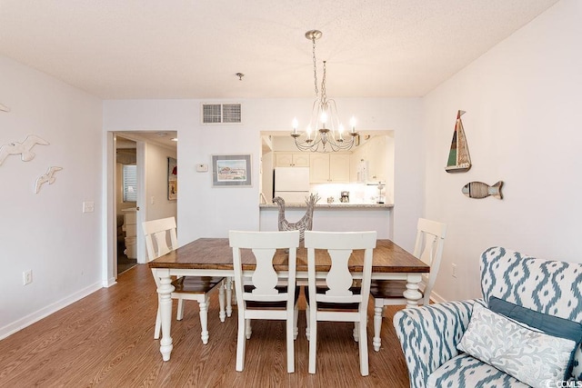 dining space featuring a chandelier, wood finished floors, and baseboards