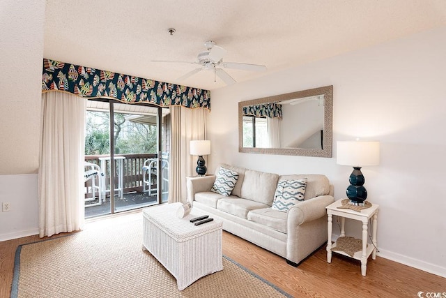 living room with a ceiling fan, baseboards, and wood finished floors