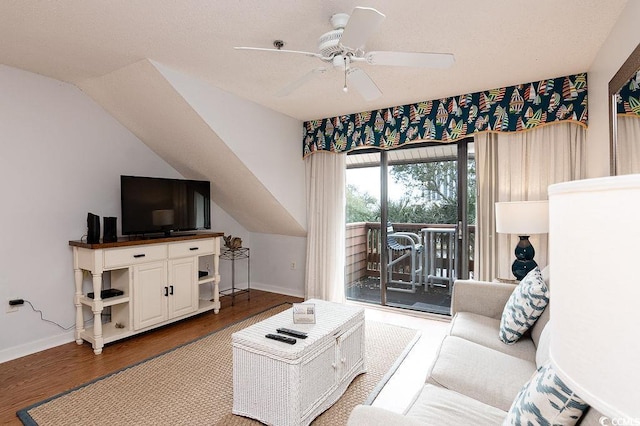 living area featuring wood finished floors, ceiling fan, baseboards, and vaulted ceiling