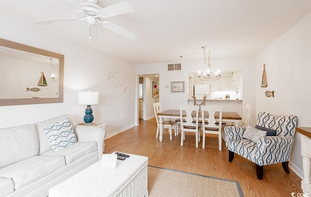 living room featuring light wood finished floors, a chandelier, a ceiling fan, and baseboards