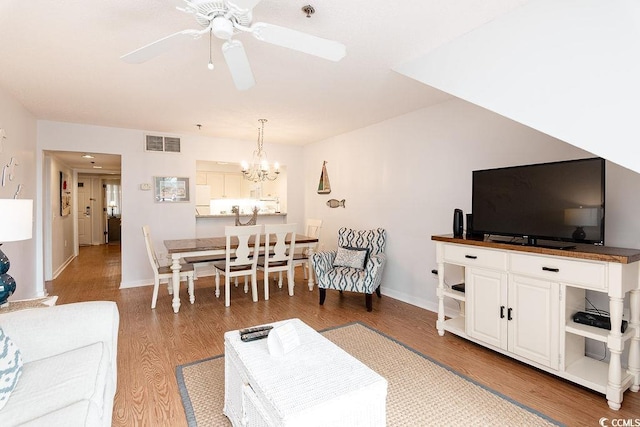 living area with wood finished floors, a ceiling fan, a chandelier, and baseboards