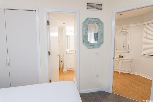 bedroom with baseboards, wood finished floors, and ensuite bath