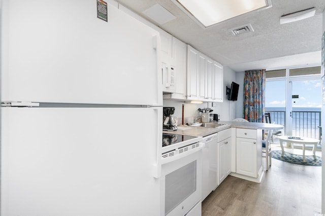 161 Seawatch Dr Unit 808, Myrtle Beach, SC 29572 - kitchen with white appliances, visible vents, a peninsula, light wood-style flooring, and a sink
