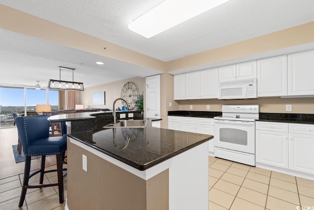 kitchen featuring white appliances, white cabinets, light tile patterned floors, and a sink