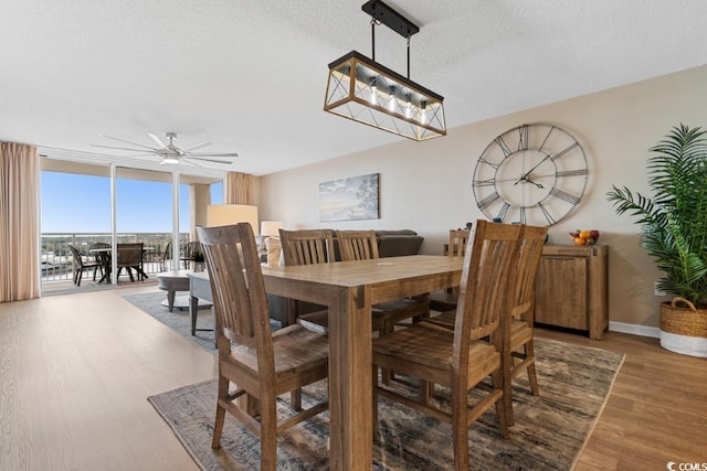 dining space with baseboards, floor to ceiling windows, wood finished floors, a textured ceiling, and a ceiling fan