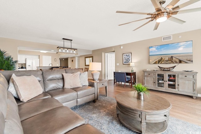 living area with a ceiling fan, light wood-style floors, and visible vents