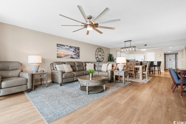 living room featuring ceiling fan, visible vents, and wood finished floors