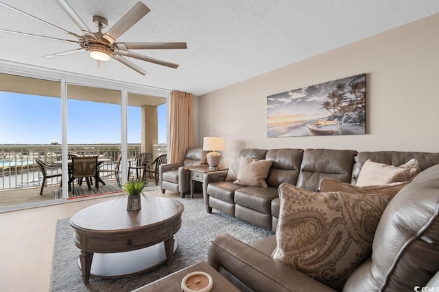 living area featuring wood finished floors, floor to ceiling windows, a ceiling fan, and a textured ceiling