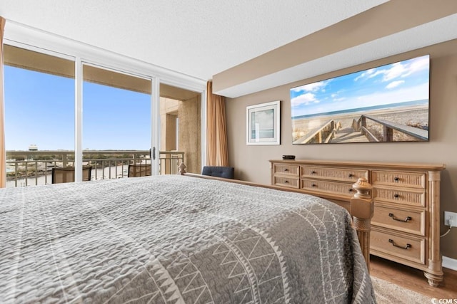 bedroom with a water view and wood finished floors