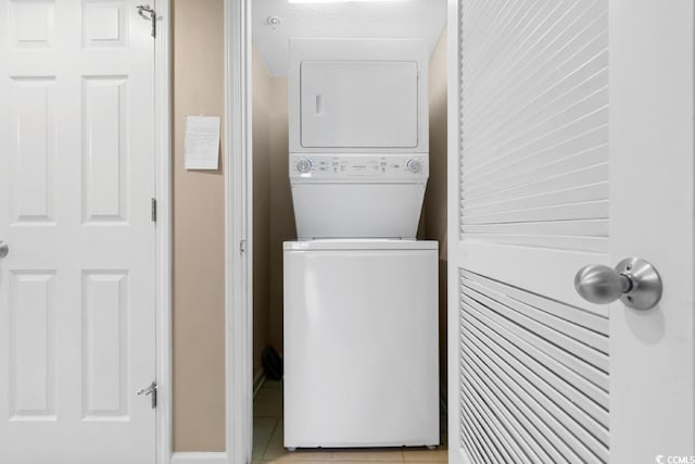 clothes washing area featuring light tile patterned floors, laundry area, and stacked washer / dryer