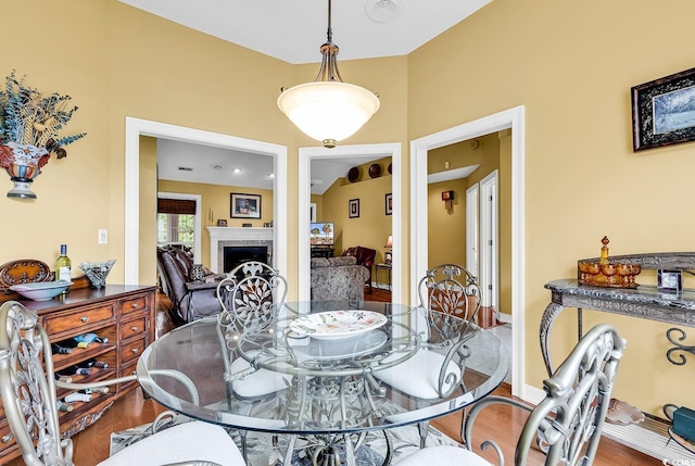 dining space featuring wood finished floors and a fireplace