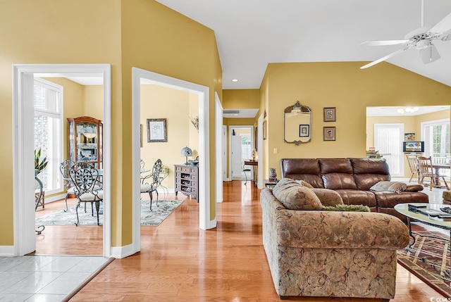 living area featuring vaulted ceiling, light wood-style flooring, and baseboards