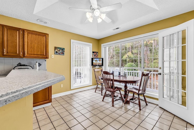 dining space with light tile patterned floors, a ceiling fan, visible vents, and a textured ceiling