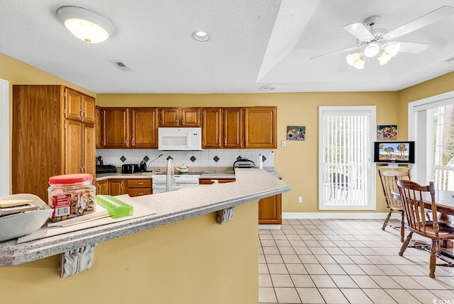 kitchen featuring white microwave, visible vents, tasteful backsplash, light countertops, and stove