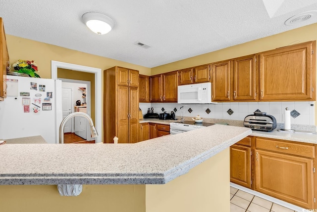 kitchen featuring white appliances, light tile patterned floors, light countertops, brown cabinets, and backsplash