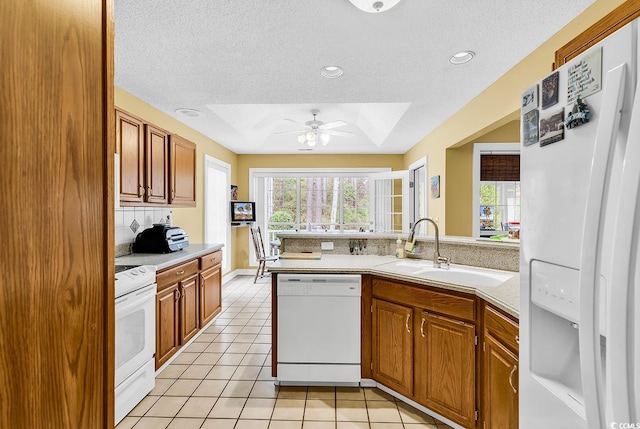 kitchen featuring a wealth of natural light, a sink, white appliances, light tile patterned flooring, and light countertops