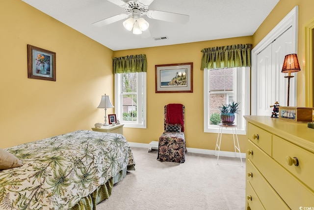 bedroom with baseboards, visible vents, ceiling fan, a closet, and light carpet