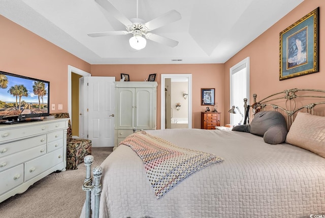 bedroom featuring visible vents, connected bathroom, carpet floors, a raised ceiling, and ceiling fan