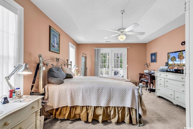 bedroom featuring light colored carpet, access to outside, ceiling fan, and a textured ceiling