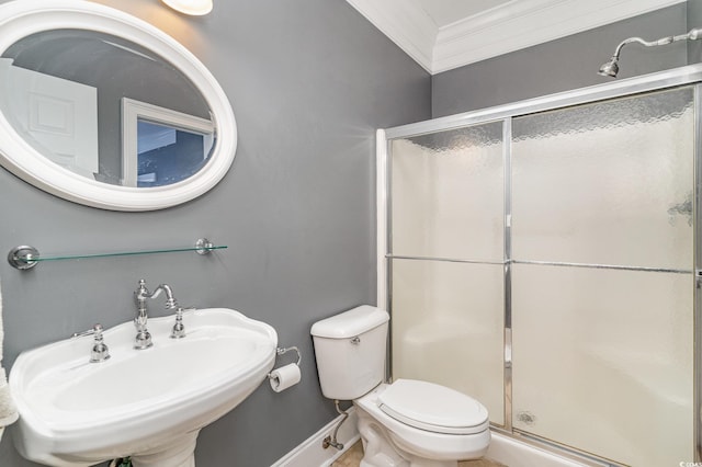 bathroom with baseboards, toilet, ornamental molding, a stall shower, and a sink