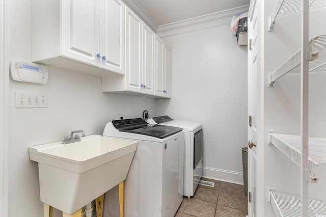 clothes washing area featuring washing machine and dryer, cabinet space, ornamental molding, light tile patterned floors, and baseboards