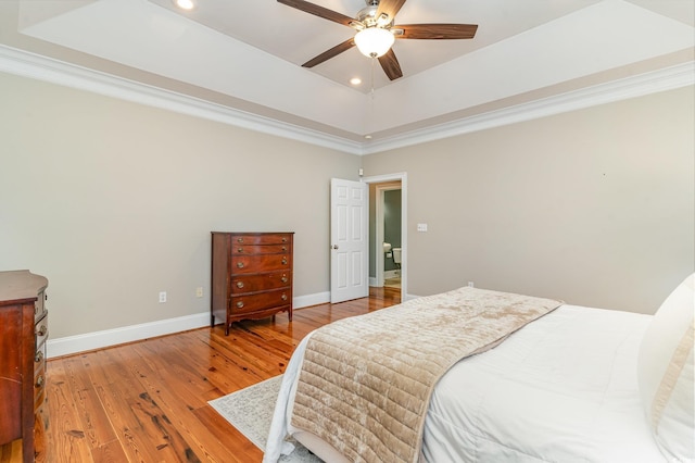 bedroom featuring recessed lighting, baseboards, wood finished floors, ornamental molding, and a raised ceiling