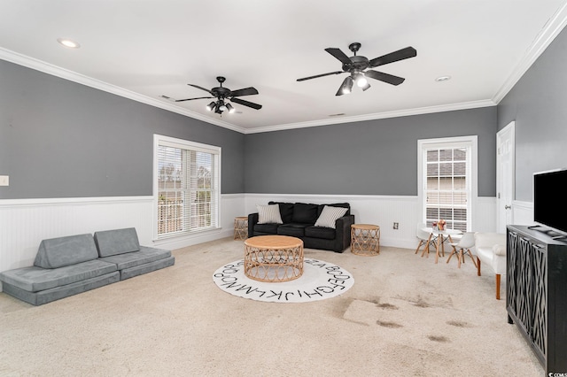 living area with crown molding, carpet flooring, and a wainscoted wall